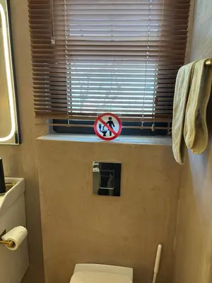 a bathroom with a toilet and a sign on a window at 3R-in-3V in Vari