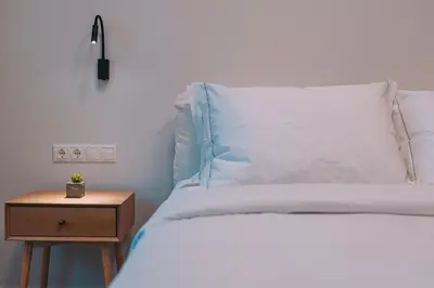 a bed with a nightstand next to a bed with a white pillow at Modern & Elegant Getaway near Pasalimani in Piraeus