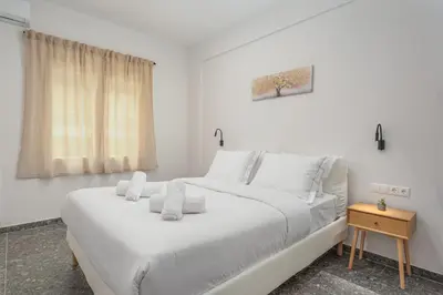 a white bedroom with a large bed with white pillows at Modern & Elegant Getaway near Pasalimani in Piraeus