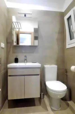 a bathroom with a toilet and a sink and a mirror at Stylish city studio by MPS in Athens
