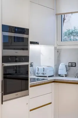 a kitchen with white cabinets and silver appliances at Alexandra's Unique Apartment in Athens