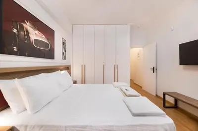 a bedroom with a white bed and a tv at Alexandra's Unique Apartment in Athens