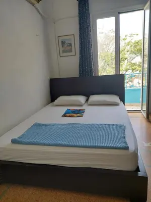 a large bed in a bedroom with a large window at SHARED ROOMS LEPENIOTU NEAR ACROPOLIS &MONASTIRAKi in Athens