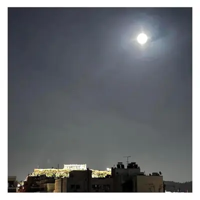 a bright moon in the sky above some buildings at Krezias Apartments ST 6 Acropolis View in Athens