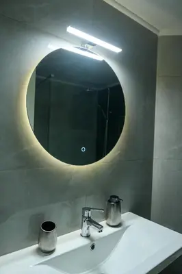 a bathroom sink with a round mirror above it at Art Squared in Athens