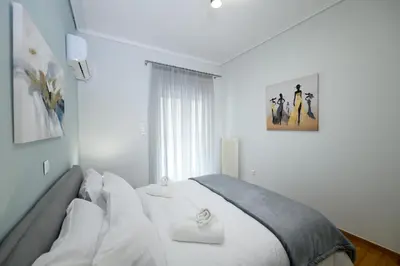 a bedroom with a bed with white sheets and a window at Art Squared in Athens