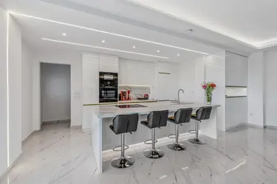 a white kitchen with a counter and stools at Sea Breeze Retreat with Private Pool in Saronida