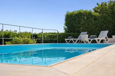 a swimming pool with chairs and a swimming pool at Sea Breeze Retreat with Private Pool in Saronida