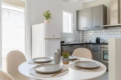 a white kitchen with a table with chairs and a white refrigerator at Cozy Penthouse with Balcony in Athens