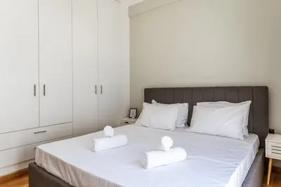 a bedroom with a white bed with two white towels at Cozy Penthouse with Balcony in Athens