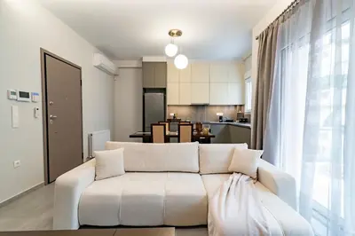 a living room with a white couch and a kitchen at Electra's apartments in Piraeus