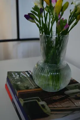 a vase with flowers on top of a stack of books at The Ilisian Estia in Athens