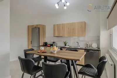 a kitchen with a wooden table and chairs at Jaax Apartment Airport by Airstay in Spáta