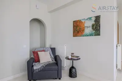 a chair in a room with a painting on the wall at Jaax Apartment Airport by Airstay in Spáta