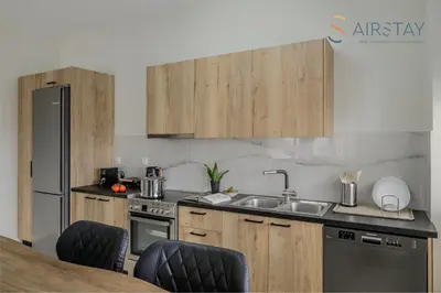 a kitchen with wooden cabinets and a sink at Jaax Apartment Airport by Airstay in Spáta
