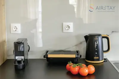 a counter with a coffee maker and some tomatoes on it at Jaax Apartment Airport by Airstay in Spáta