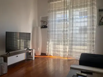 a living room with a large window and a television at Cozy flat in the heart of Athens in Athens