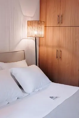 a bedroom with a white bed with a lamp and cabinets at Alme Sélas in Port Rafti in Porto Rafti