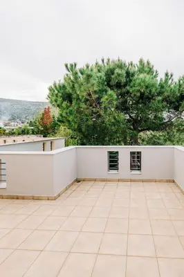 an empty patio with a white wall and trees at Alme Sélas in Port Rafti in Porto Rafti