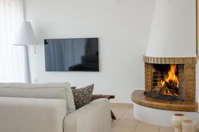 a living room with a couch and a fireplace at Alme Sélas in Port Rafti in Porto Rafti
