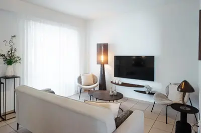 a living room with a white couch and a tv at Alme Sélas in Port Rafti in Porto Rafti
