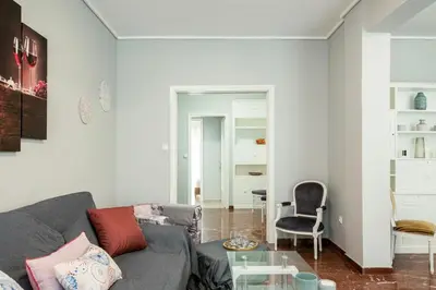 a living room with a gray couch and a glass table at AthensHomes Spacious Comfort Metro apt 3Br 2Ba in Athens