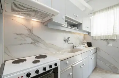a white kitchen with a stove and a sink at AthensHomes Spacious Comfort Metro apt 3Br 2Ba in Athens