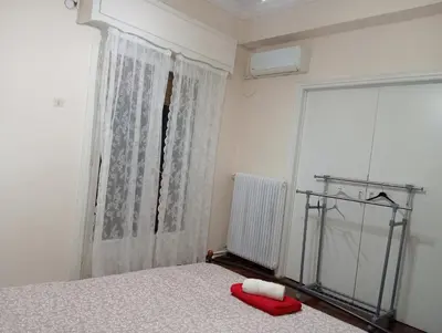 a bedroom with a bed with a red pillow and a window at Room Z for two 5' from metro in Athens