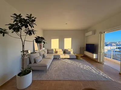 a living room with a couch and a tv at Sunny Downtown Glyfada Penthouse in Athens