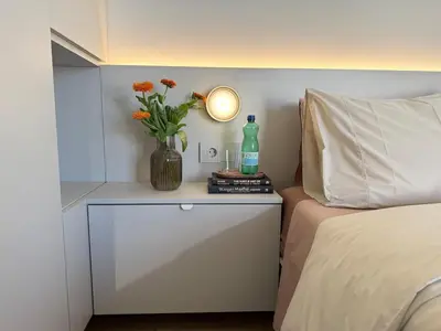 a table with a vase with flowers and a bottle on it at Sunny Downtown Glyfada Penthouse in Athens