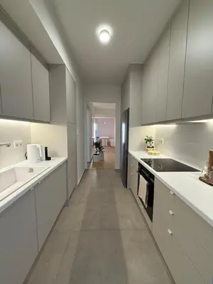 a kitchen with white cabinets and a long hallway at Sunny Downtown Glyfada Penthouse in Athens