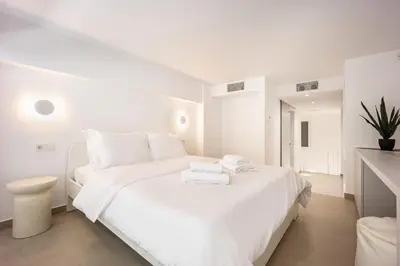 a white bedroom with a large bed with white sheets at Downtown Properties Loft 2 in Athens