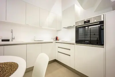 a white kitchen with white cabinets and a microwave at Downtown Properties Loft 2 in Athens