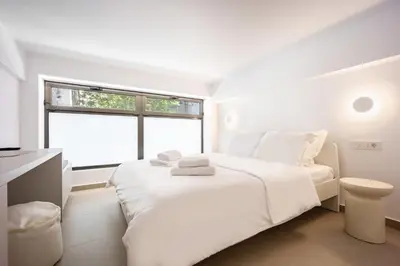 a white bedroom with a bed and a window at Downtown Properties Loft 2 in Athens