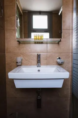 a white sink in a bathroom with a mirror at Piraeus Port Hotel in Piraeus