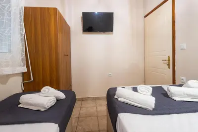 a room with two beds and a tv on the wall at Fantasea Porto Rafti on the sea 15 minutes from the airport in Porto Rafti