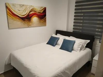 a white bed with blue pillows and a painting on the wall at Cozy 1-Bedroom Flat in the Heart of Athens by ΜΡS in Athens
