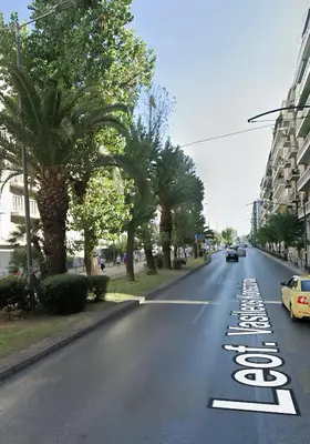 an empty street with palm trees and cars on the road at Panathenaic Athens Center Apartment in Athens
