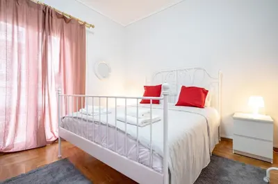 a bedroom with a white bed with red pillows at Spacious 3-Bedroom Apartment in Neos Kosmos by ΜΡS in Athens