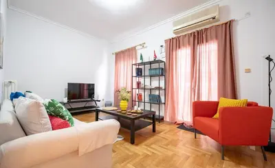 a living room with a white couch and a red chair at Spacious 3-Bedroom Apartment in Neos Kosmos by ΜΡS in Athens