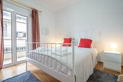 a bedroom with a white bed with red pillows at Spacious 3-Bedroom Apartment in Neos Kosmos by ΜΡS in Athens