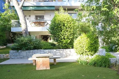 a bench sitting in the grass in front of a building at Summer Vacation Home in Vouliagmeni for 4 by Filos Inc in Athens