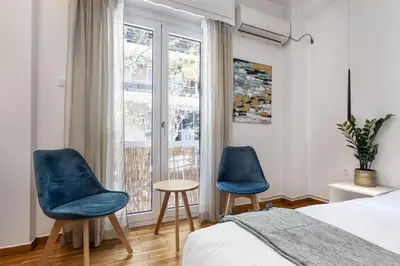 two blue chairs in a bedroom with a bed and a window at Viora - Stunning Deluxe Studio in Athens in Athens