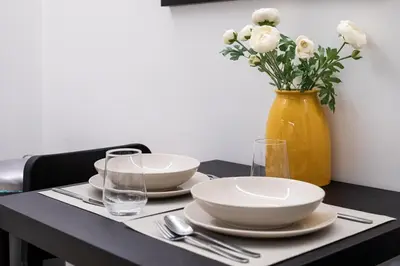 a table with plates and a yellow vase with flowers at Viora - Stunning Deluxe Studio in Athens in Athens