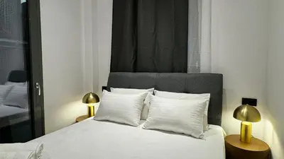 a bedroom with a bed with white pillows and two lamps at Downtown Modern Studio in Athens