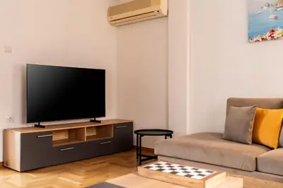 a living room with a television and a couch at Athenian Living in the Heart of Koukaki in Athens