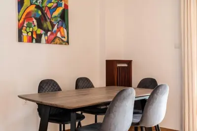 a dining room table with chairs and a painting at Athenian Living in the Heart of Koukaki in Athens