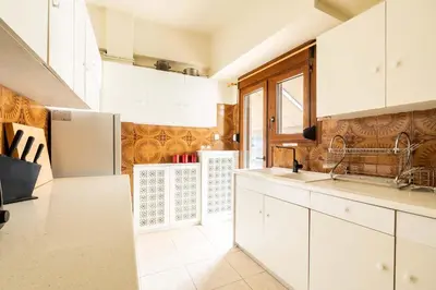 a kitchen with white cabinets and a refrigerator at Athenian Living in the Heart of Koukaki in Athens