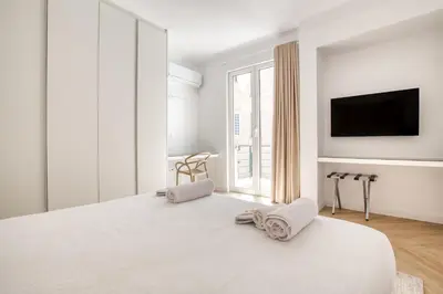a white bedroom with a bed and a tv at Whitewood Residence in Athens