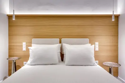 a bed with two white pillows and two stools at Whitewood Residence in Athens